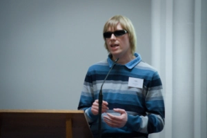 David Shervill standing behind a podium giving a talk. 