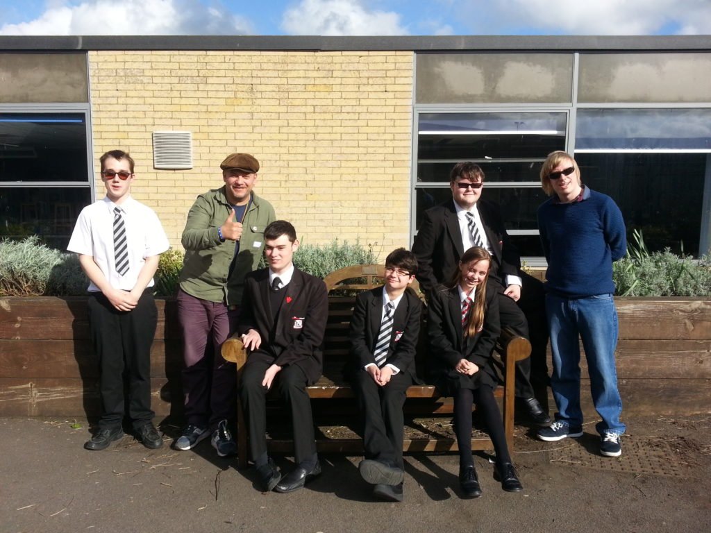 Members of the group with Jim and David, having a group photo in the playground, for the CD cover.