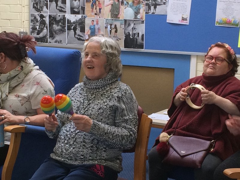 A picture of participants playing tambourine and maracas.