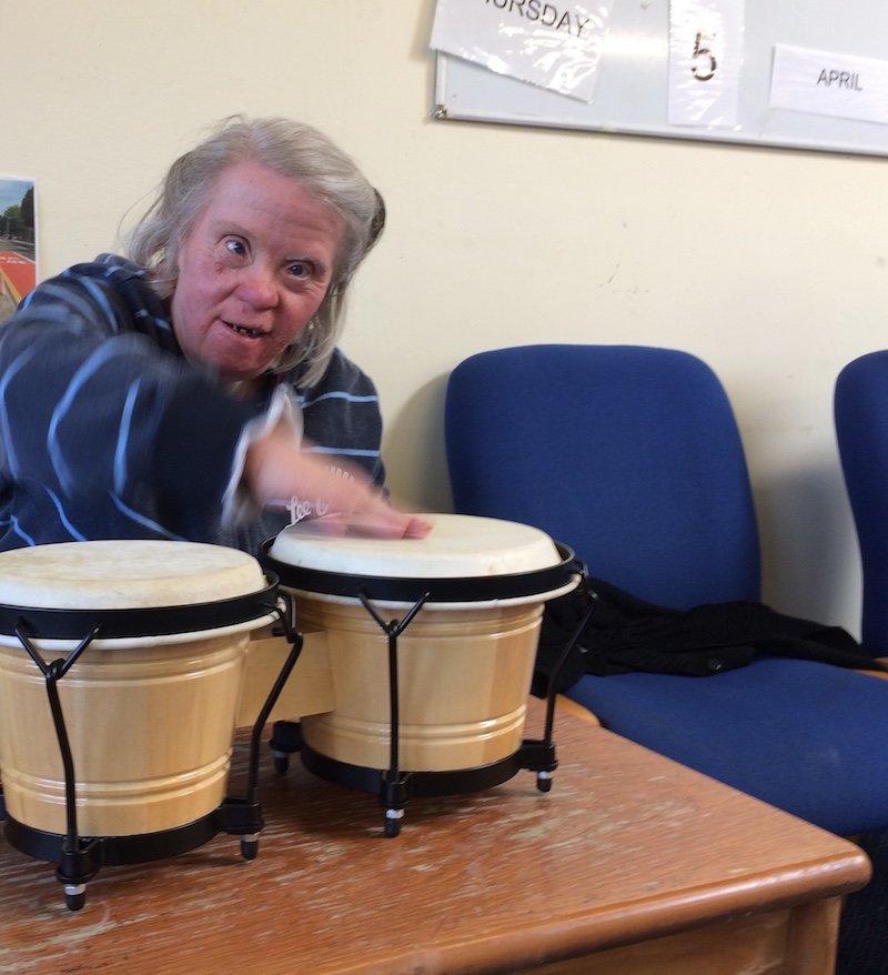 A picture of a participant playing the Bongo Drums, during the session.
