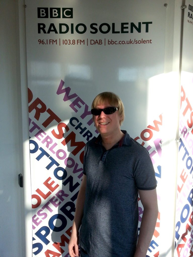 Included is a picture of David, standing in front of the BBC Radio Solent banner. 