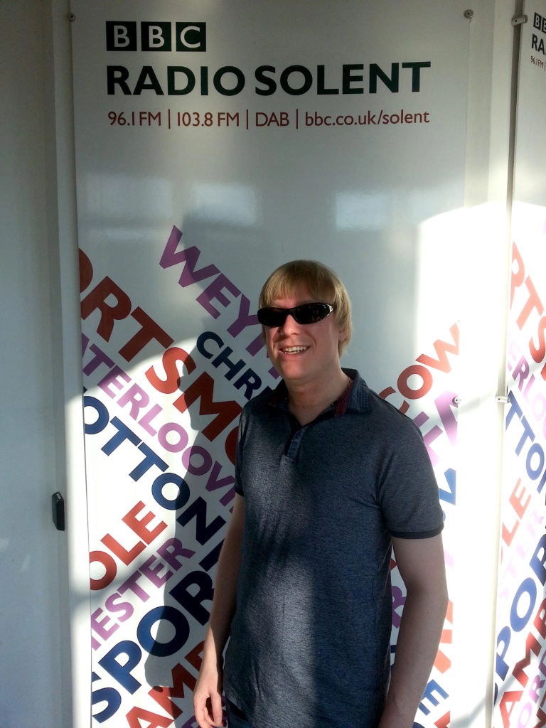 Included is a picture of David, standing in front of the BBC Radio Solent banner.