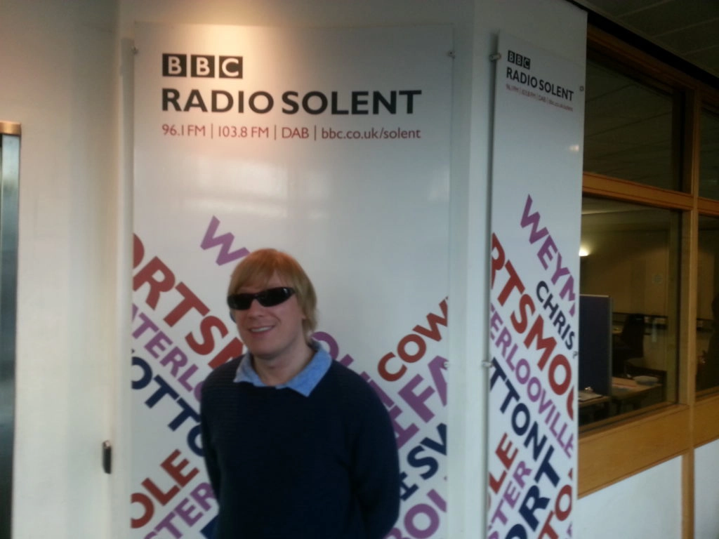 Included is a picture of David standing in front of the BBC Radio Solent banner.