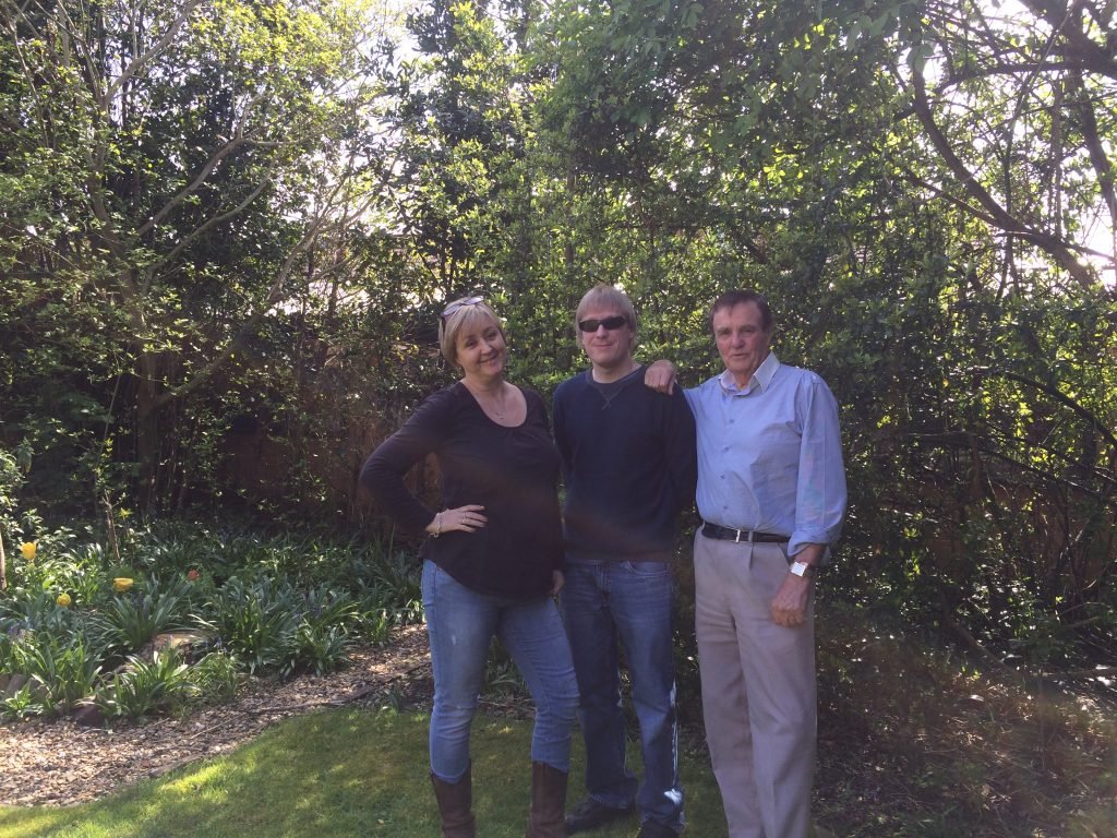 Included is a picture starting from left to right of Rachel Goodall, David Shervill, and Nelson Ward, standing on grass with green trees and bushes behind them. 