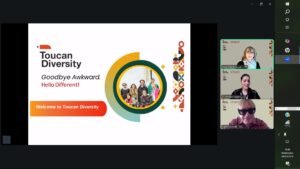 A screenshot of a Zoom Meeting showing a Toucan Diversity presentation slide that reads, “Goodbye Awkward. Hello different!” and “Welcome to Toucan Diversity.” Three participants are visible on the right with branded ‘Toucan Diversity’ virtual backgrounds.